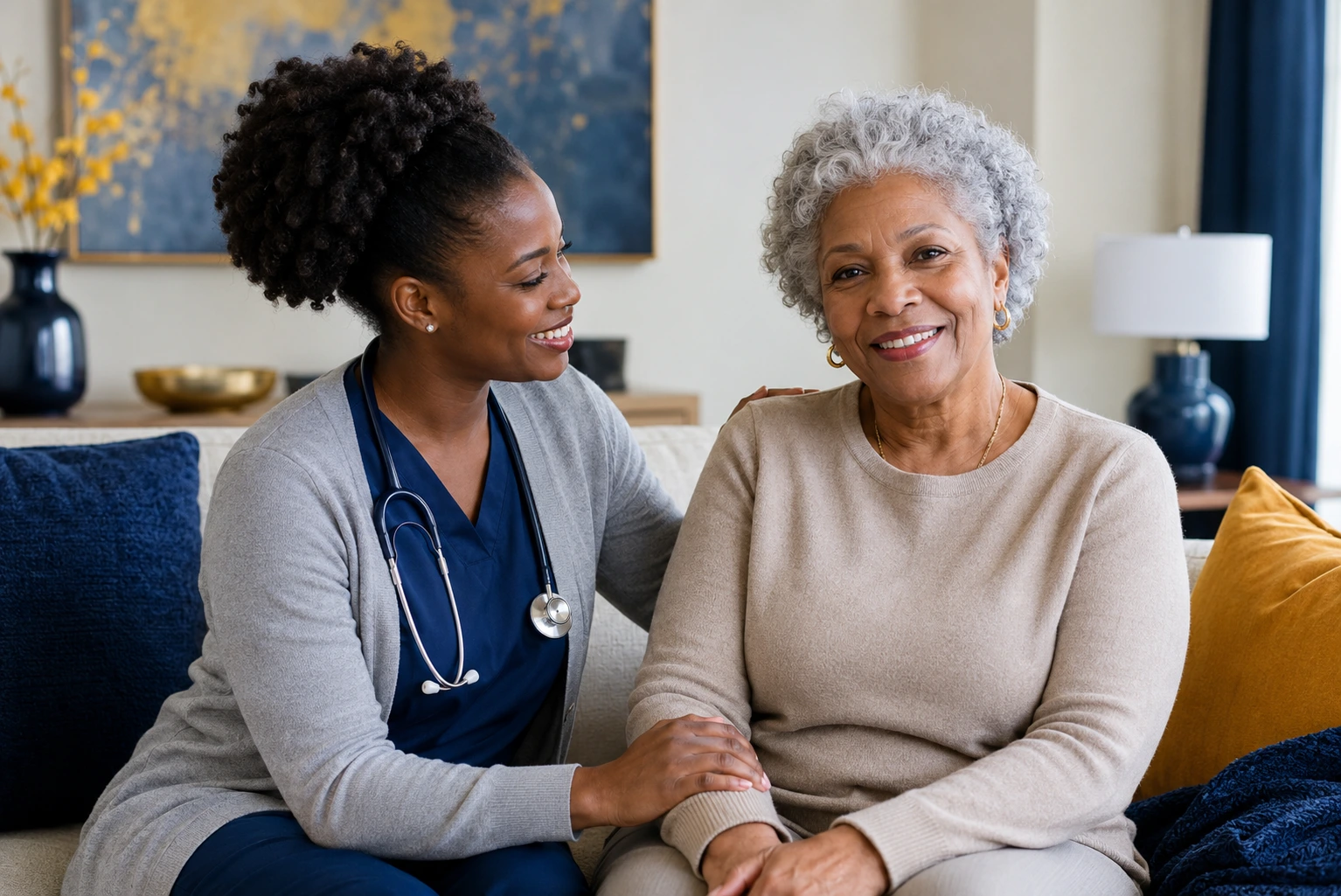 African American home health nurse smiling while gently supporting a senior patient in a cozy living room with deep blue and gold accents.